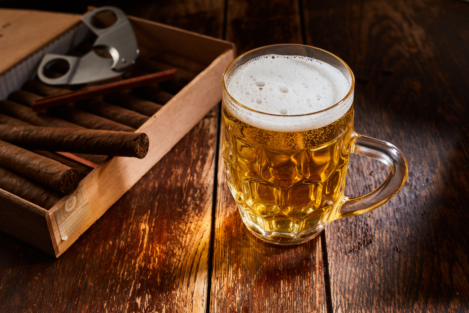 Beer in glass on wooden table with cigars